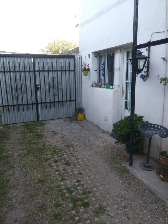 a fence next to a white house with a yard at Alojamiento Libertador in Alta Gracia