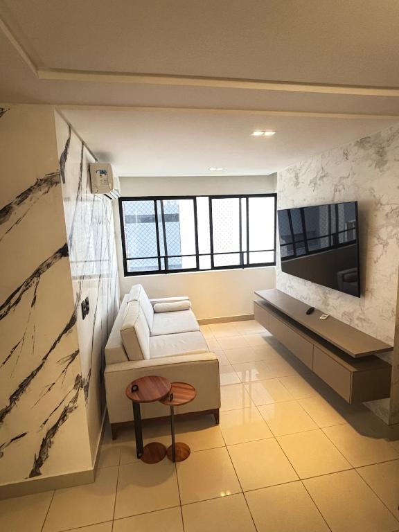 un salon avec un canapé blanc et une télévision dans l'établissement Alto do Juruá 302, à Natal