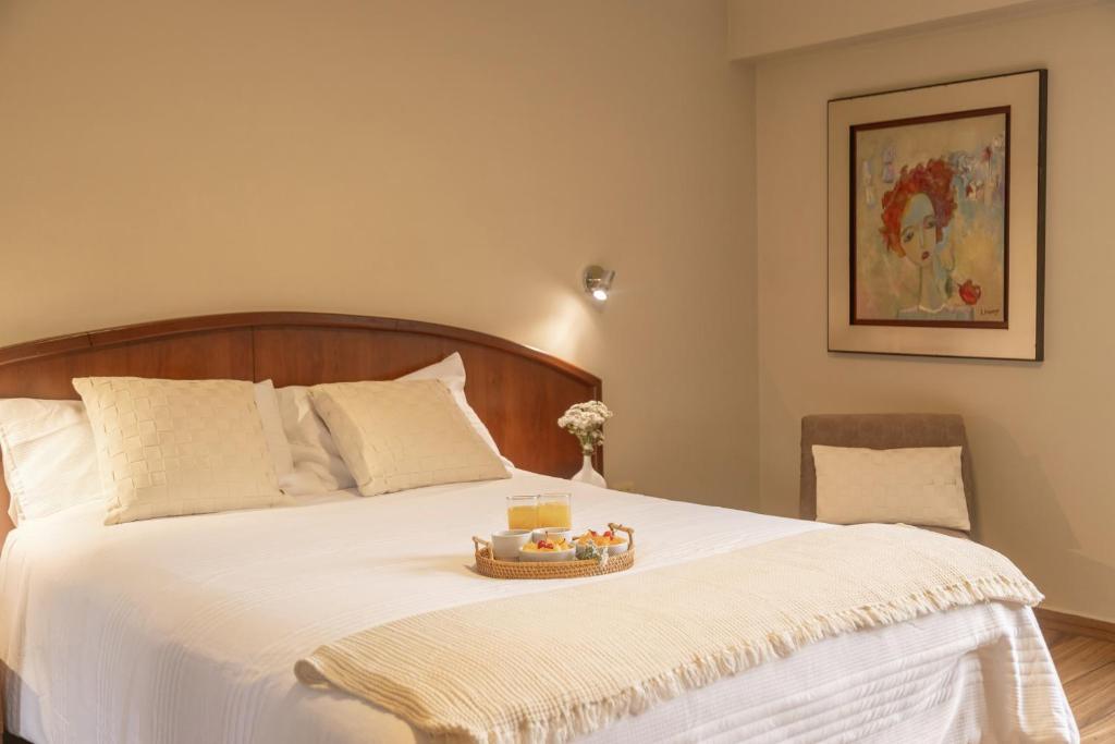 a bedroom with a bed with a tray of food on it at Hotel Park Suites in Lima