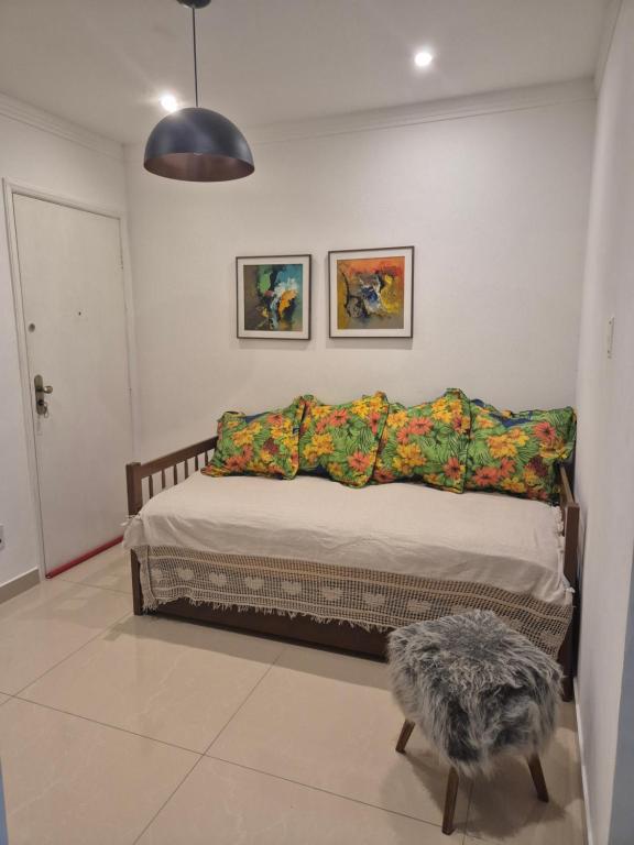 a bed in a room with two pictures on the wall at Apartamento na Praia in Praia Grande