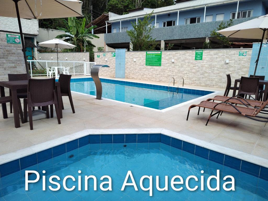 a swimming pool with a table and chairs next to a building at Canto Verde Aptos II in Caraguatatuba