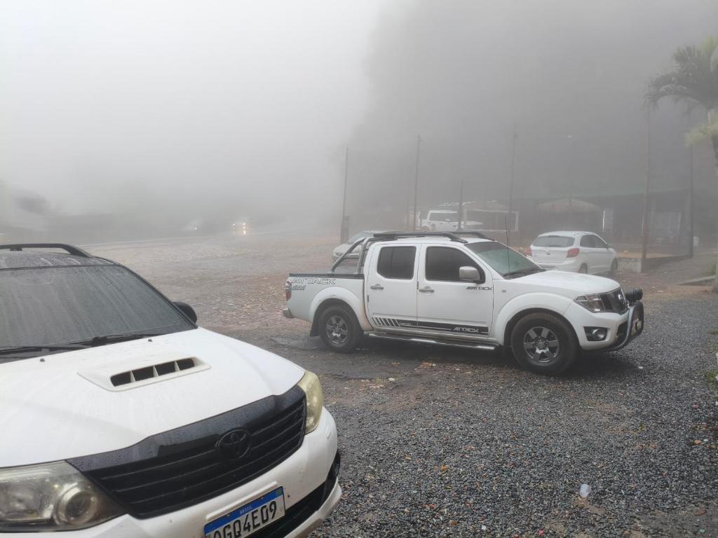 two white cars parked in a parking lot in the fog at Balneário cascata chalés in Tianguá