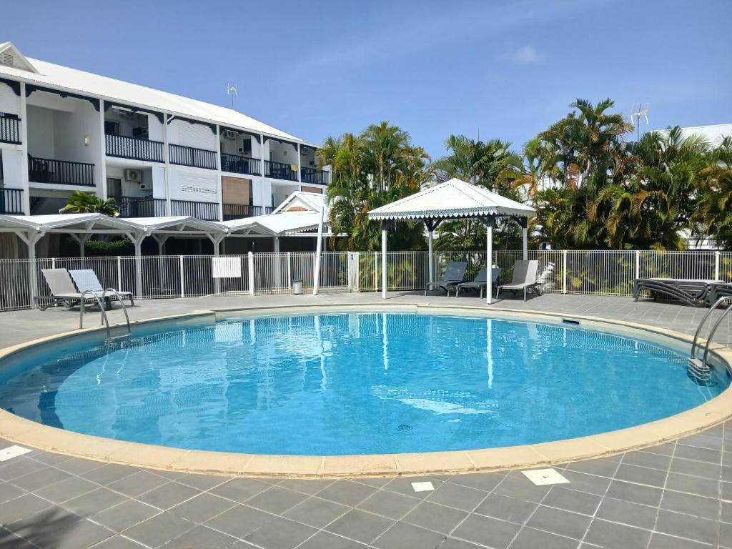 a large blue swimming pool in front of a building at Studio Le Sablé in Îlet à Christophe