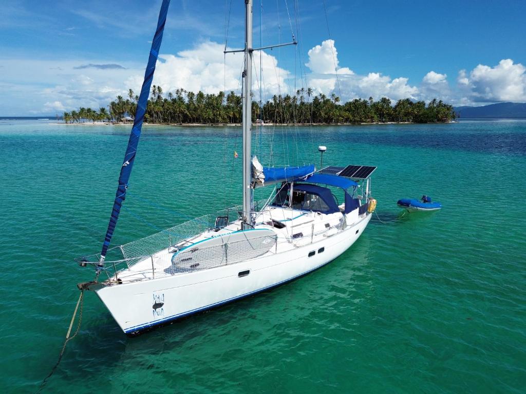 Un velero blanco en el agua con una isla. en mola mola, en Playón-Chico