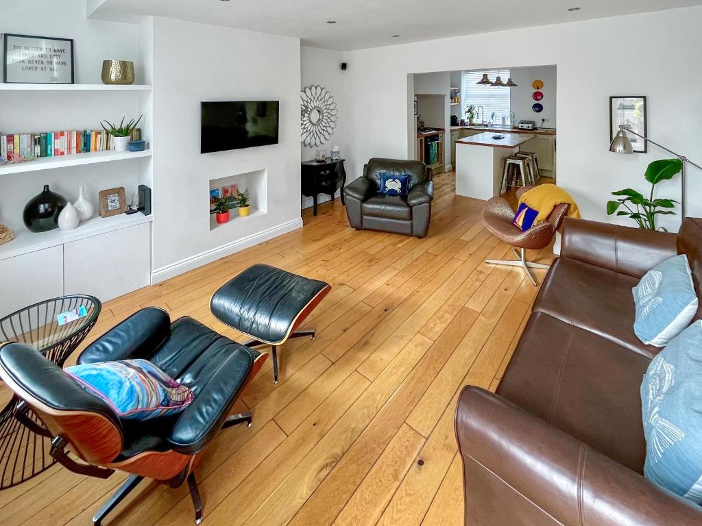 a living room with a leather couch and chairs at Pebble Cottage in Cullercoats