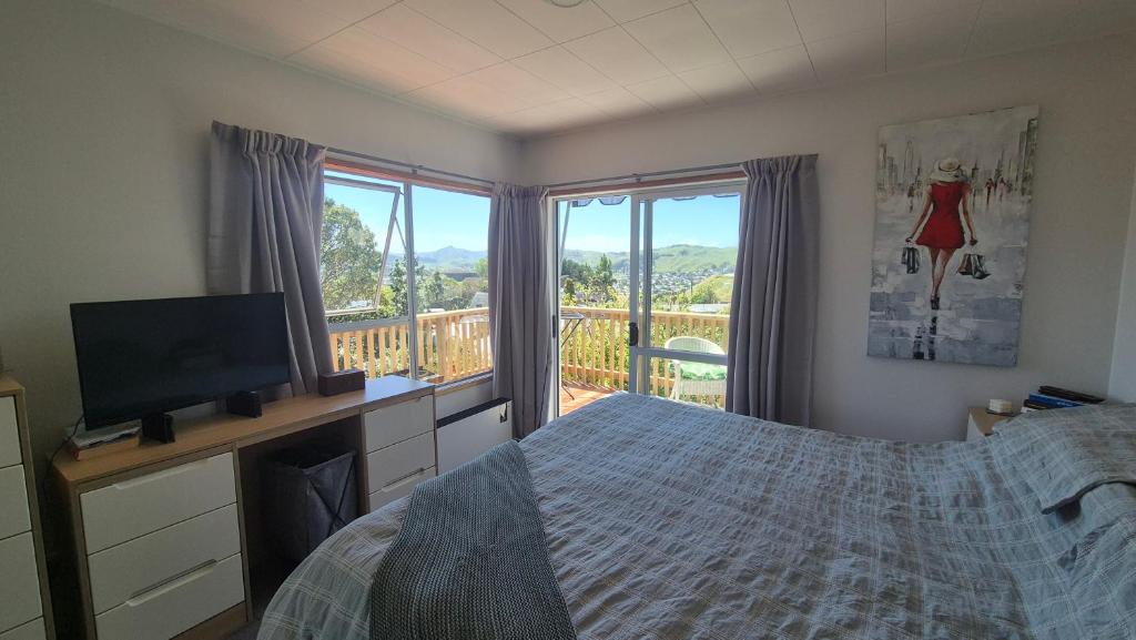 a bedroom with a bed and a television and a balcony at Turanga Heights in Gisborne