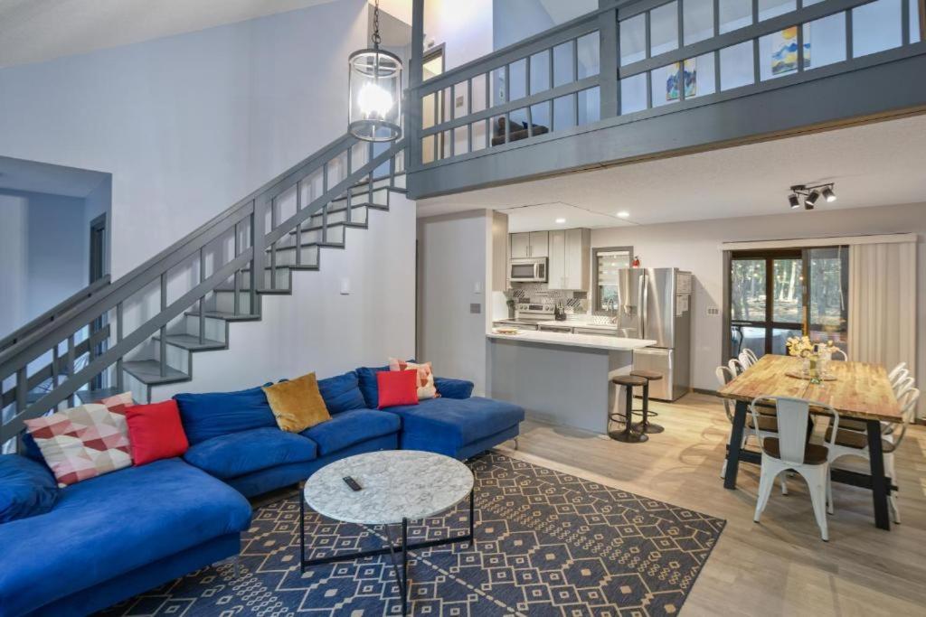 a living room with a blue couch and a staircase at 4BD Cabin in the Poconos Near Lake with Hot Tub, Sauna, Game Room and Movie Room in East Stroudsburg