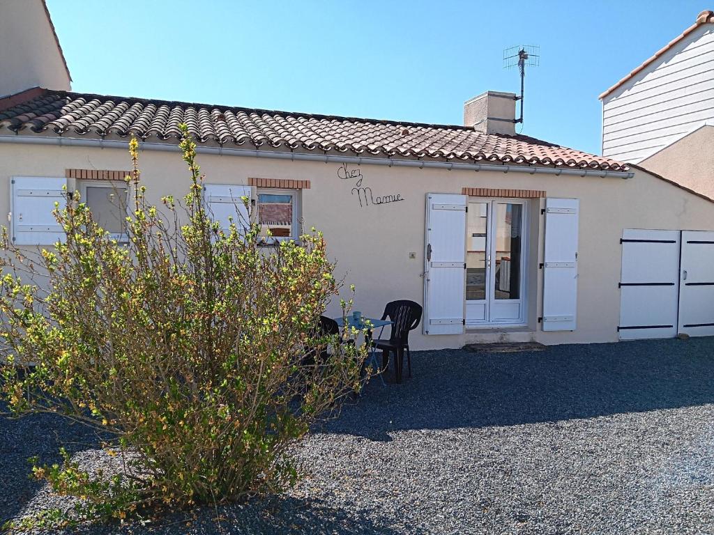 ein weißes Haus mit einem schwarzen Stuhl davor in der Unterkunft Maison calme pour 4 personnes avec jardin - FR-1-476-111 in Grues