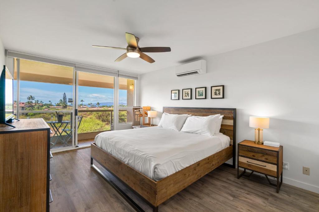 a bedroom with a bed and a large window at Oceanview King Studio - Maui Banyan, Walk to Beach in Wailea