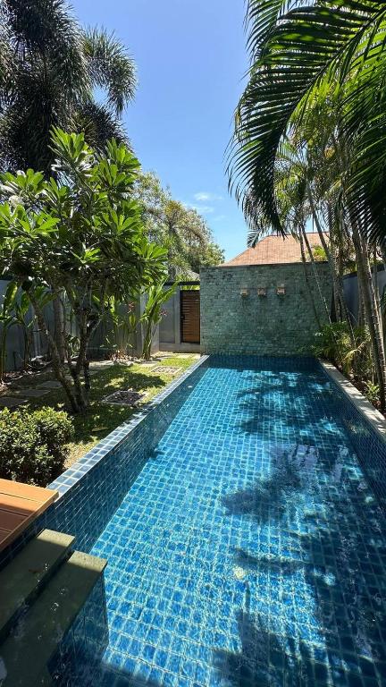 a swimming pool in a yard with palm trees at Cozy villa - perfect place to stay in Phuket in Ban Saiyuan (1)