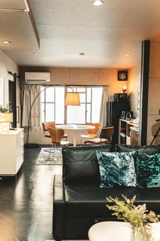 a living room with a black couch and a kitchen at Vinyl Stay - spacious local apartment in Osaka