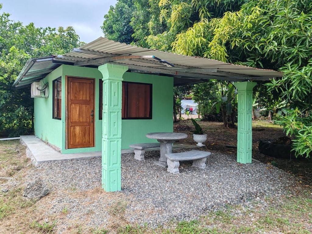 a small green house with a bench and a table at Playa Blanca Puerto Jiménez in Puerto Jiménez