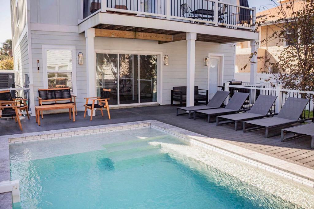 a swimming pool on a patio with chairs and a house at Slow Pace Beach Living - Pool - Steps from Beach in Jacksonville Beach
