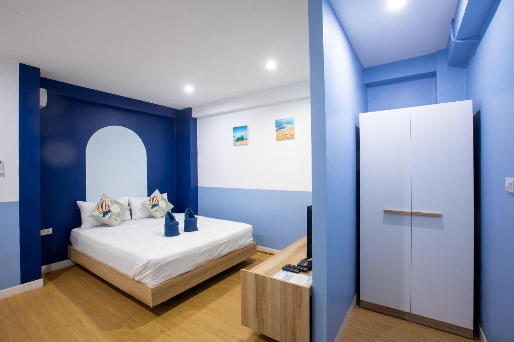 a bedroom with blue walls and a bed with white sheets at PanoSea Bangsaen in Ban Bang Saen (1)