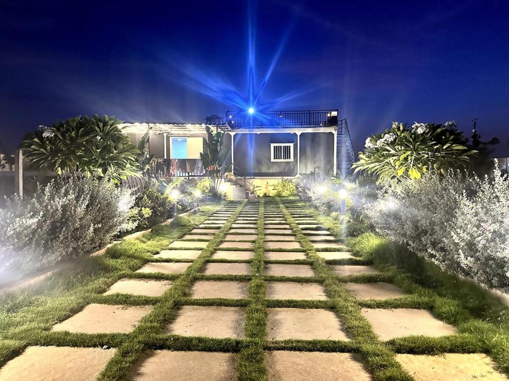 a pathway in a garden at night with lights at Aasa Farmhouse in Hyderabad