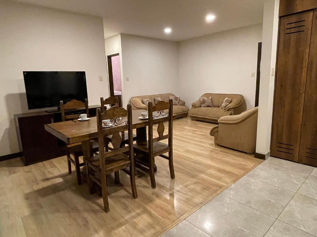 a living room with a table and chairs and a television at Cómodo y acogedor departamento amoblado in Cochabamba
