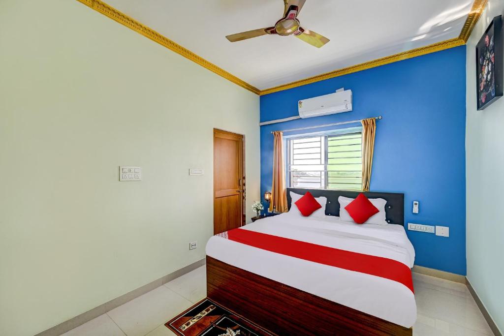 a bedroom with blue walls and a bed with red pillows at Hotel O GD STAY INN 1 in Bhubaneshwar