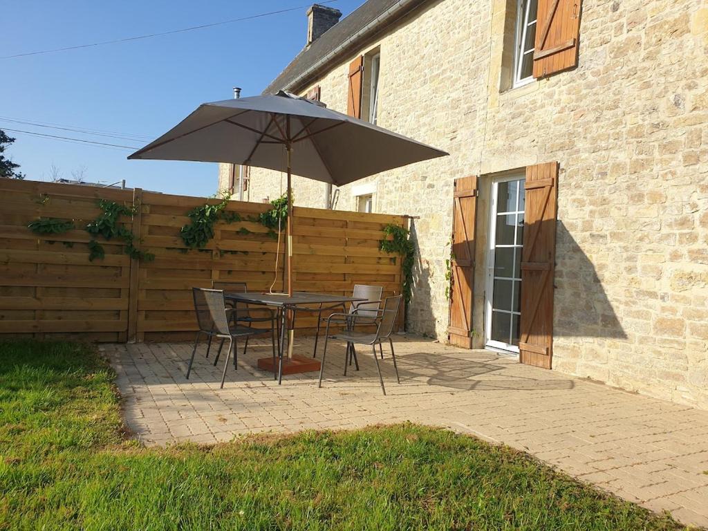 ein Tisch und Stühle mit einem Sonnenschirm auf einer Terrasse in der Unterkunft lefevre cottage, Landing beaches house in Saint-Pierre-du-Mont