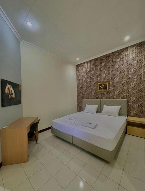 a bedroom with a large bed and a desk at Hotel New Pesona Anggraini in Brujul