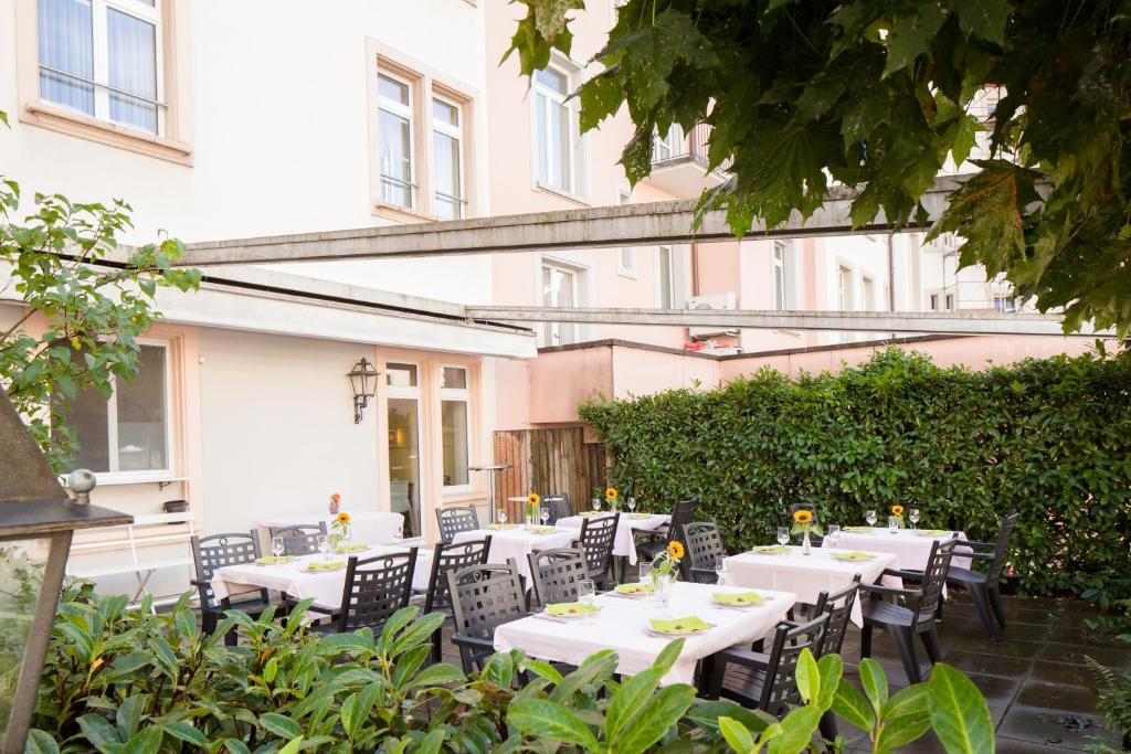 an outdoor patio with white tables and chairs at Hotel Ambassador in Solothurn