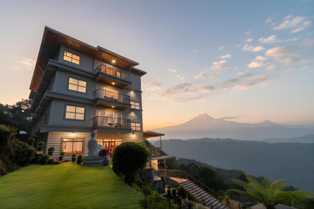 a house on a hill with a mountain in the background at Summit Enigma Resort & Spa , Lamahatta in Darjeeling
