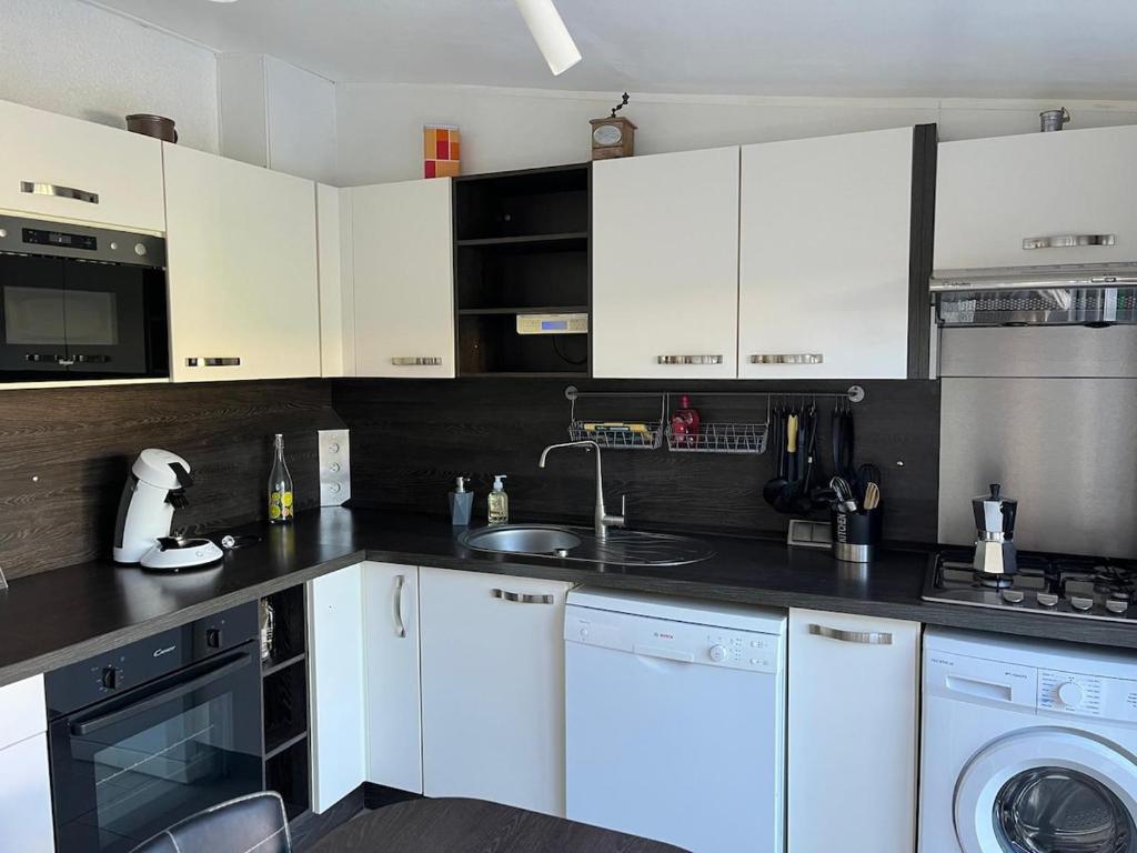 a kitchen with white cabinets and a sink at Maisonnette privé bord de mer Poggio mezzana in Poggio-Mezzana