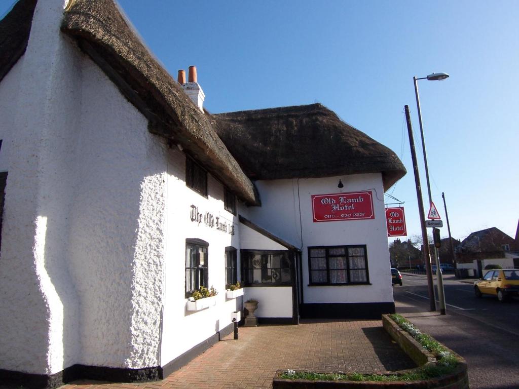 a white building with a thatched roof on a street at Old Lamb Hotel in Reading