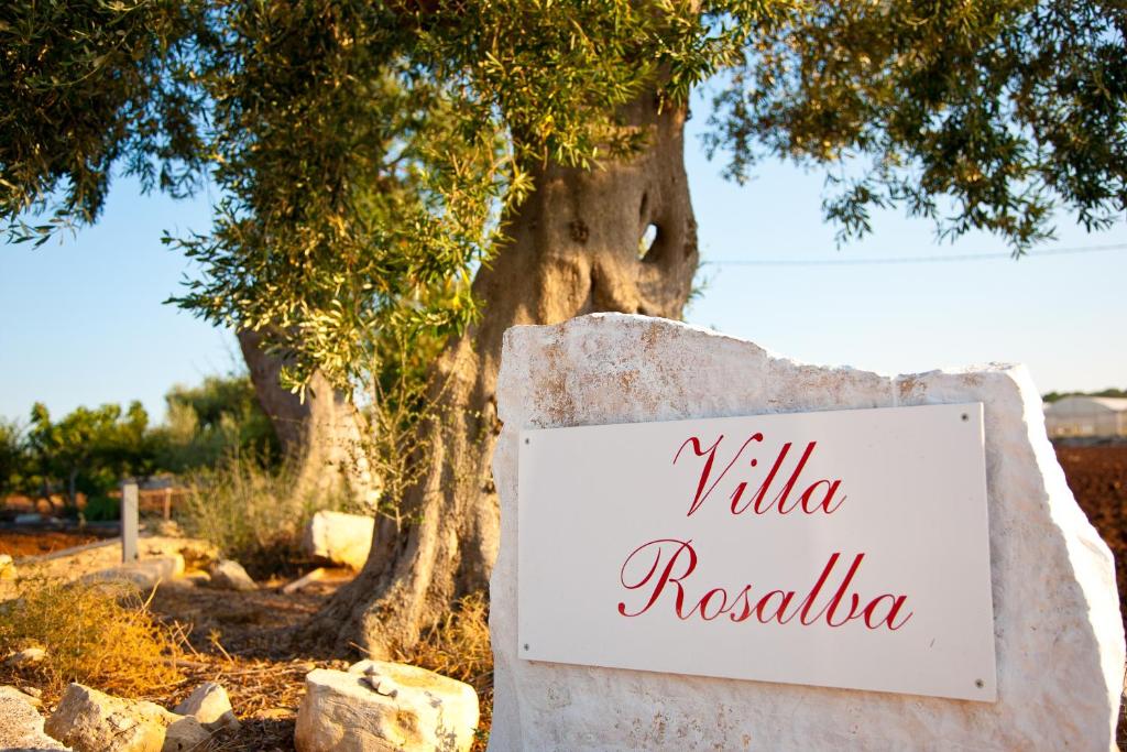 a sign on a wall in front of a tree at Villa Rosalba in Polignano a Mare