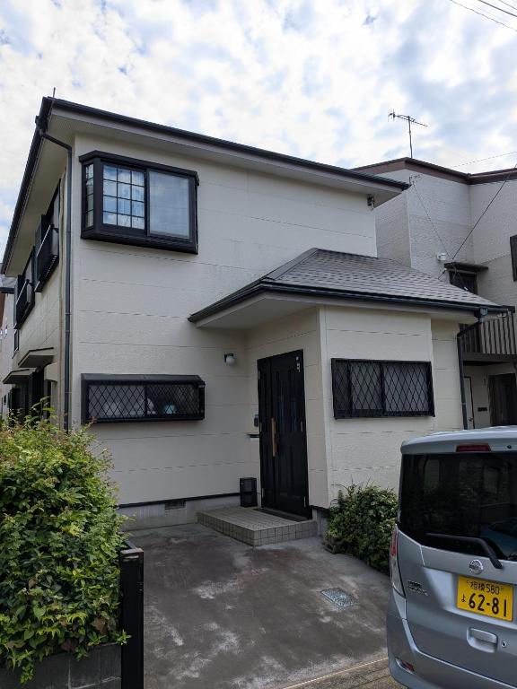 a white house with a car parked in front of it at いちごハウス in Zushi