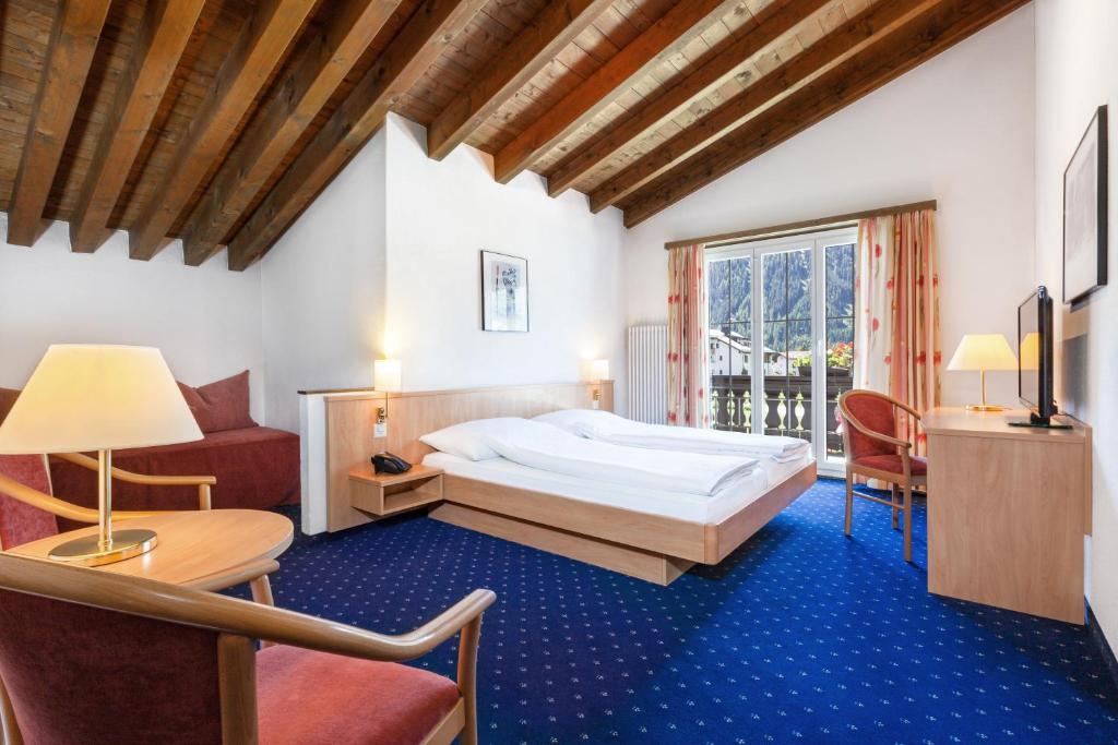 ダボスにあるHotel Bünda Davosのベッドルーム1室(ベッド1台、テーブル、椅子付)