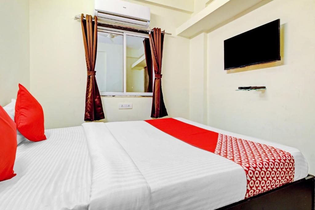 Cette chambre comprend un lit blanc avec des oreillers rouges et une télévision. dans l'établissement Hotel O Pioneer 2, à Hinjawadi