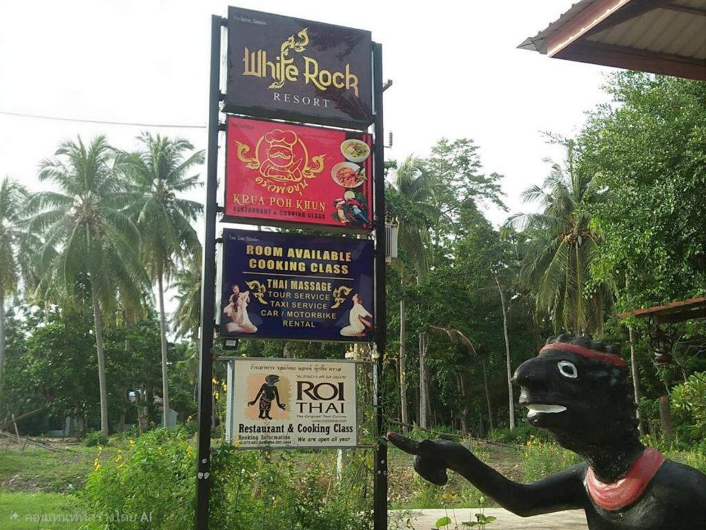 ein Schild mit einer Hundestatue daneben in der Unterkunft ลันตาไวท์ร็อค รีสอร์ท in Ban Nong Chaeng