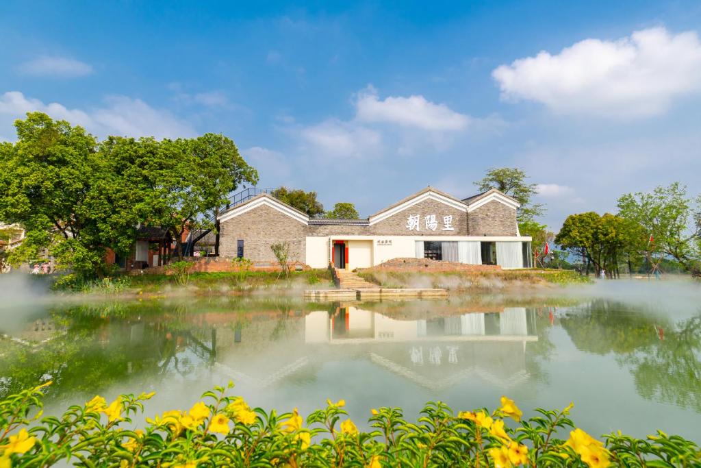 a house with a pond in front of it at Chaoyangli Folk Resort Hotel in Zhaoqing