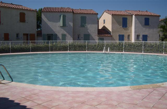 a large swimming pool in front of some buildings at La Paloma in Aigues-Mortes