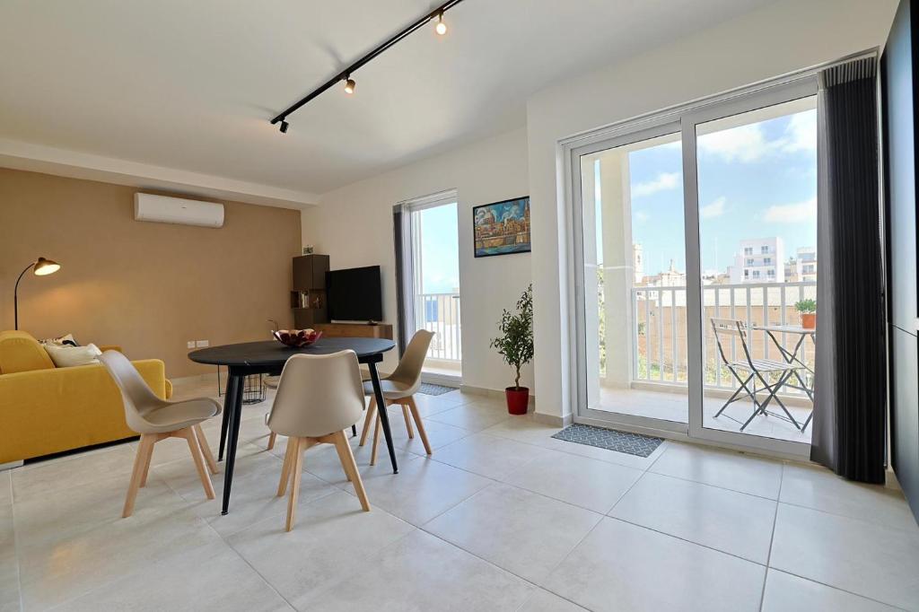 a living room with a table and chairs and a couch at St Paul's Apt Distant SeaViews in St. Paul's Bay