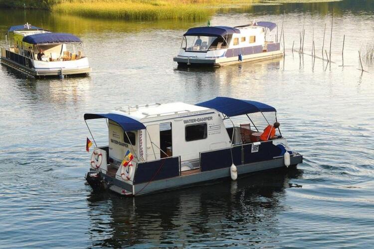 VerchenにあるHouseboat on the Peene in Demminの三隻の船が水の中に停泊している
