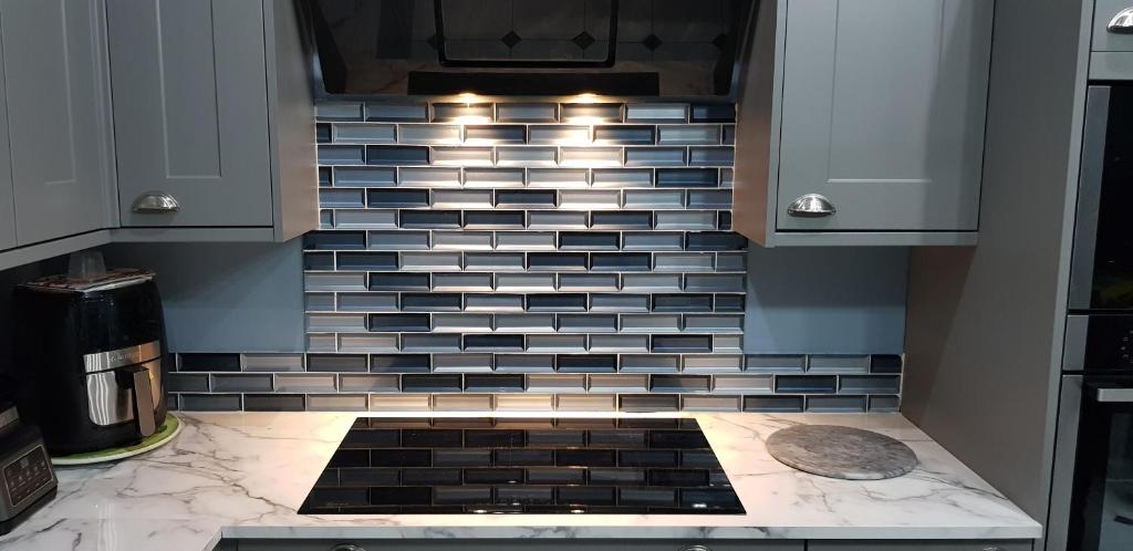 a kitchen with a black and white tile back splash at BUDGET ROOMS - 9 East Grange Drive in Leeds