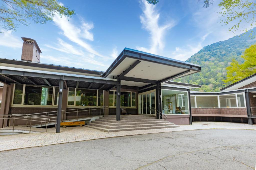 a building with awning on it with mountains in the background at Kyukamura Nikko-Yumoto in Nikko