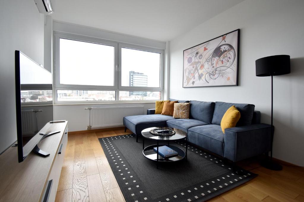 a living room with a blue couch and a table at Panorama Studio in Novi Sad