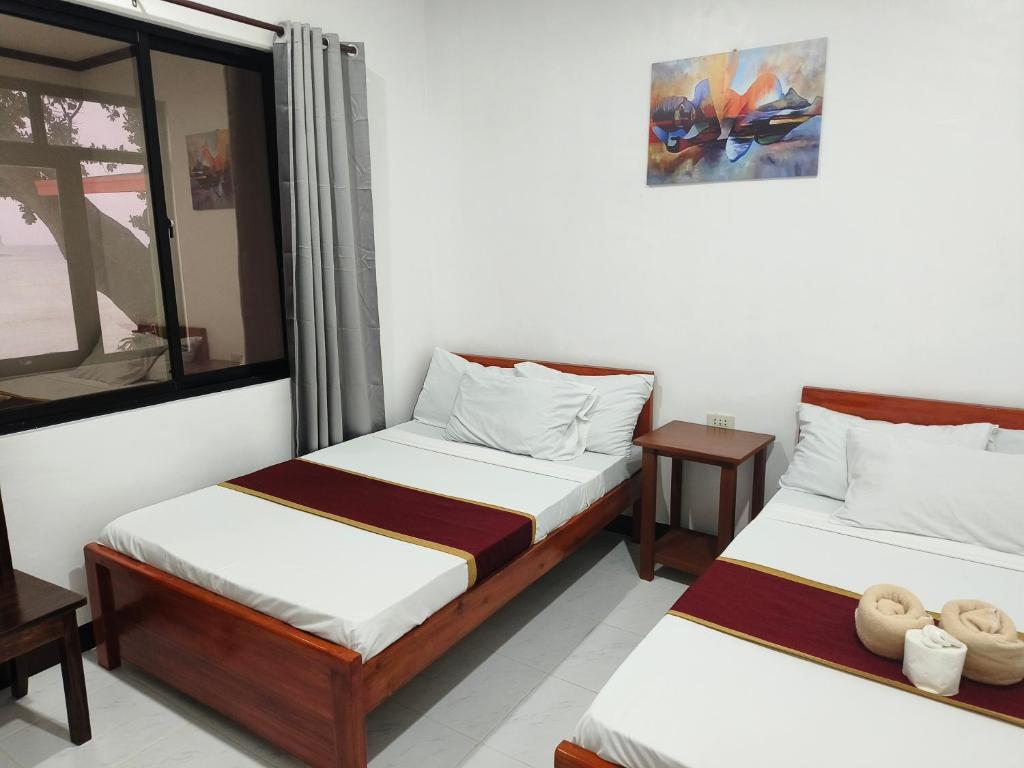 une chambre avec deux lits et une fenêtre dans l'établissement Hadefe Cottages Beach Front, à El Nido