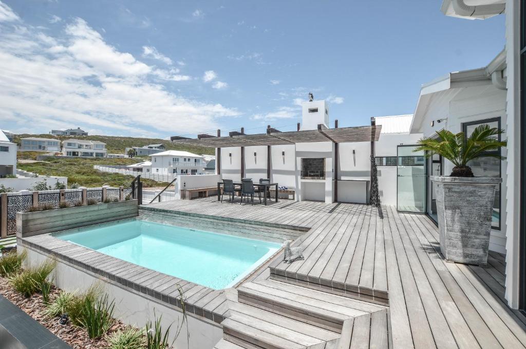 a patio with a swimming pool on a wooden deck at Sandbanks Villa in Yzerfontein