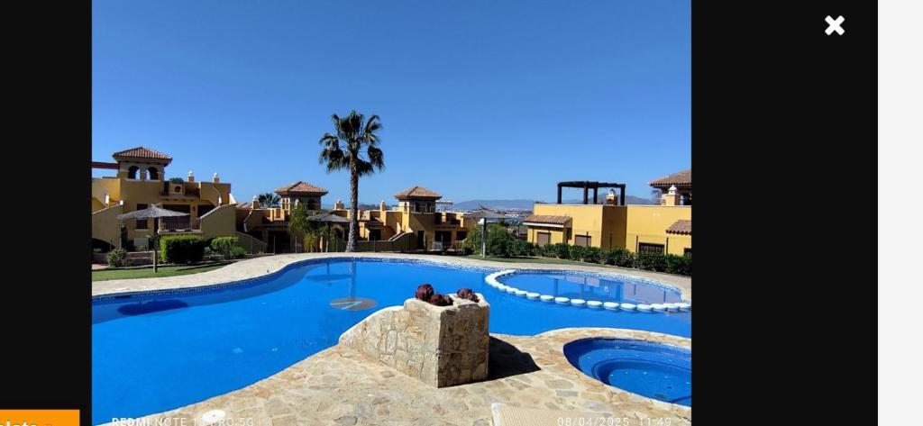 a couple sitting in front of a swimming pool at Beautiful apartment with gardens - sea and mountain views in Isla Plana