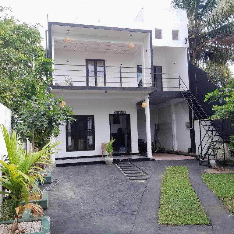 a white house with a balcony and a courtyard at Sadew Villa in Anuradhapura