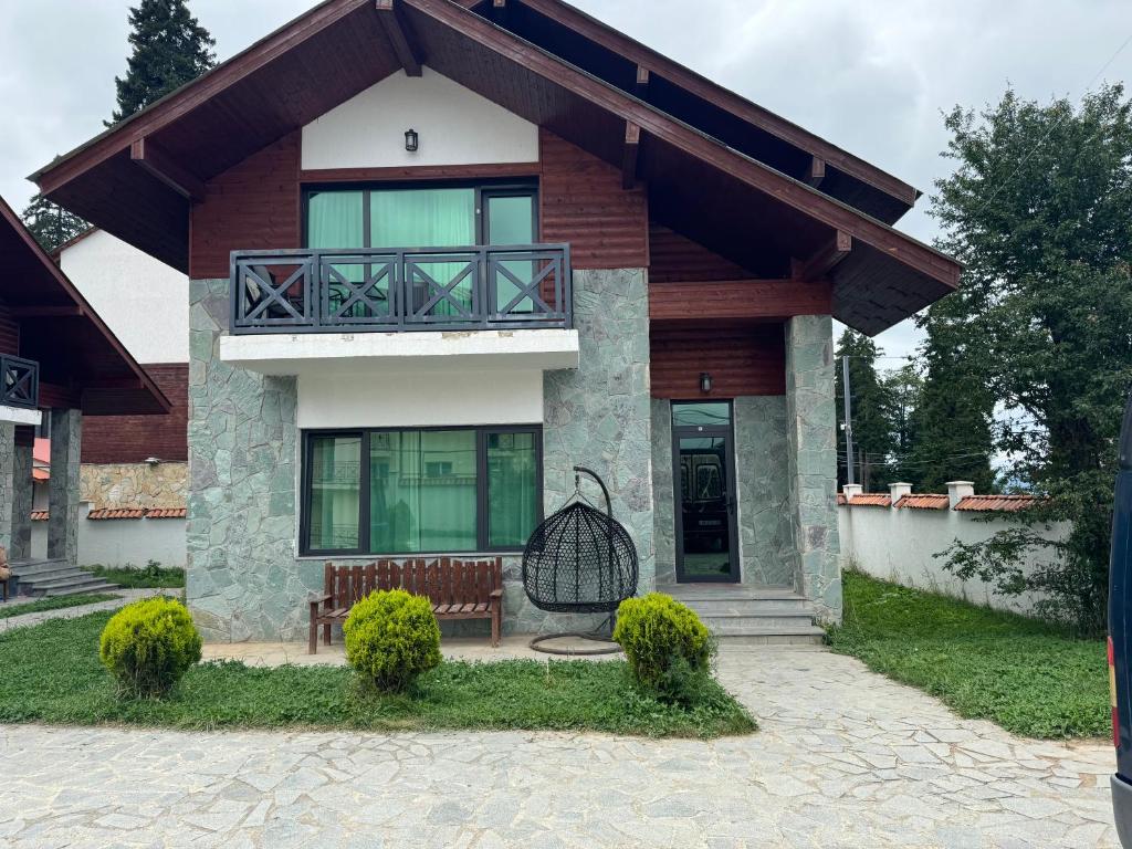 a house with a balcony and a bench in front of it at bakurian in Bakuriani