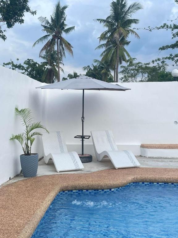 an umbrella and chairs next to a swimming pool at Hiddennest Guest house in Alcantara