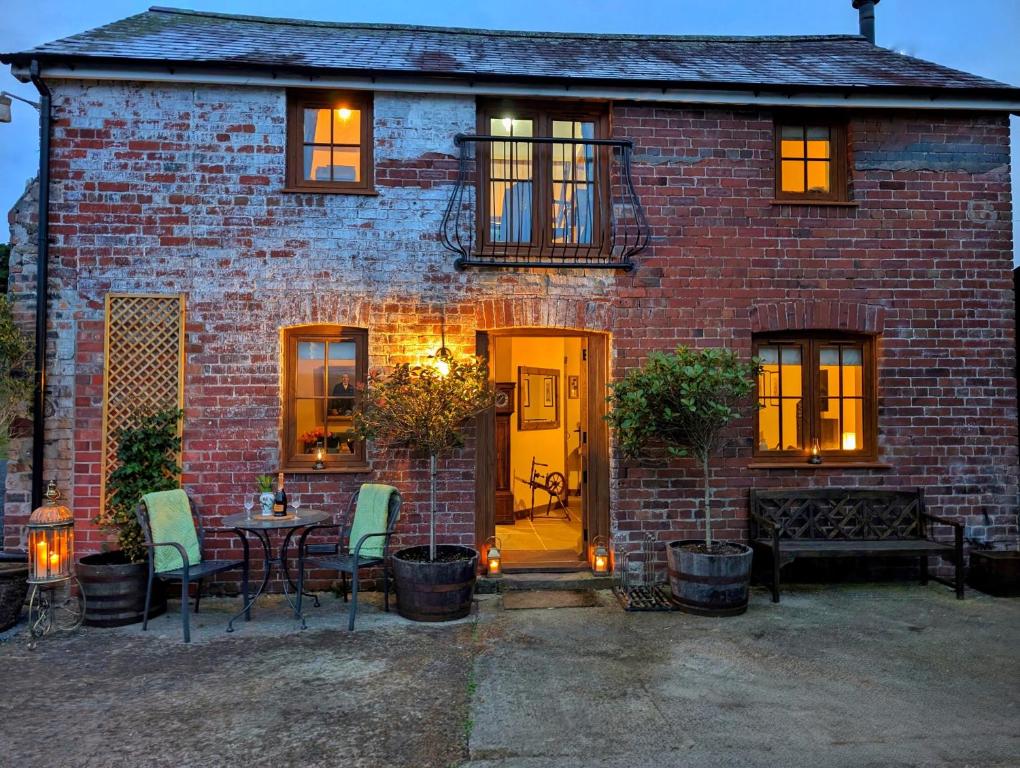 une maison en briques avec une porte jaune, une table et des chaises dans l'établissement Romantic Country Cottage with log burner, garden patio, outdoor tub and country views- Brecon Beacons National Park, à Llangadog