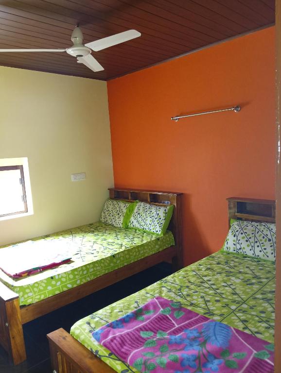 zwei Betten in einem Zimmer mit orangefarbenen Wänden in der Unterkunft TungaTeera Homestay in Sringeri