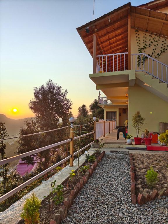 a house with a balcony with the sunset in the background at Meru Stays - A Kumaouni Homestay in Mukteshwar