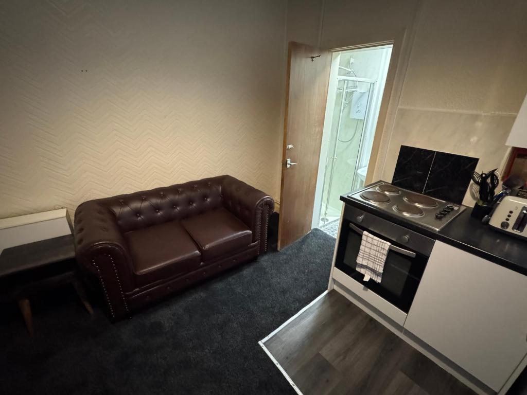 a living room with a brown leather couch and an oven at Snug Studio - Minutes Walking from Pleasure Beach - Burlington Road in Blackpool
