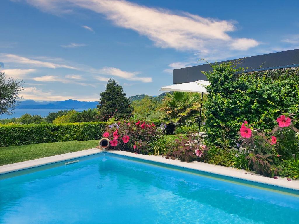 a swimming pool in a yard with flowers at LUXURY VILLA ORIZZONTI - Regarda Travel in Bardolino